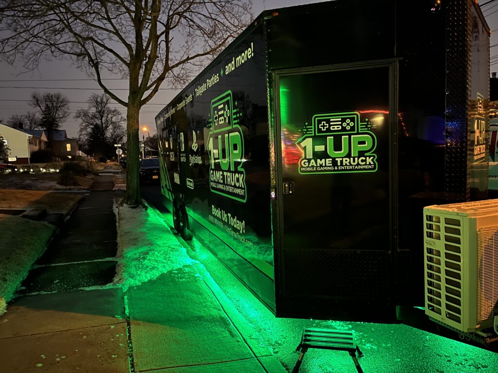 Our Truck: 1-Up Game Truck nighttime exterior view with arcade style lighting